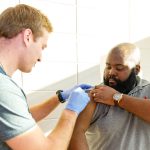 A nursing student giving a staff member the flu shot