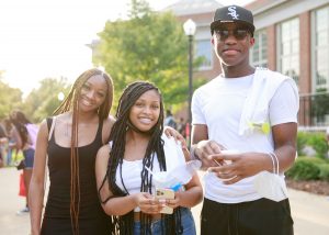three students stand together smiling outdoors at a weeks of welcome event