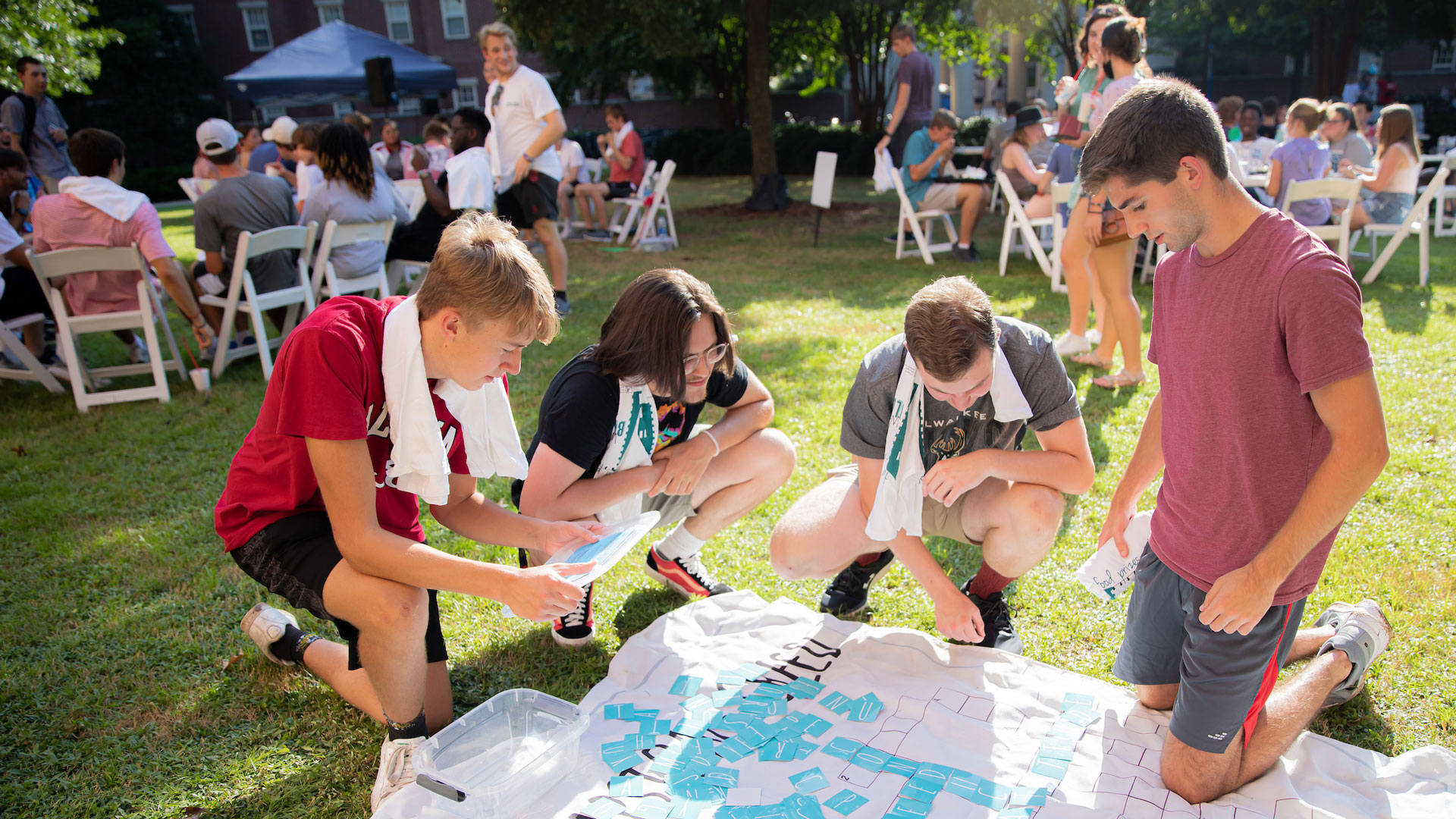 four young men play a giant crossword puzzle on the ground during a weeks of welcome event in 2021