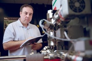 A man writes on a notebook while examining scientific equipment.