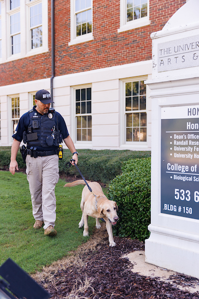 a police dog sniffs a campus sign