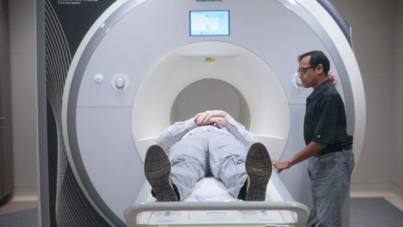 A patient lies flat on an MRI scanner.