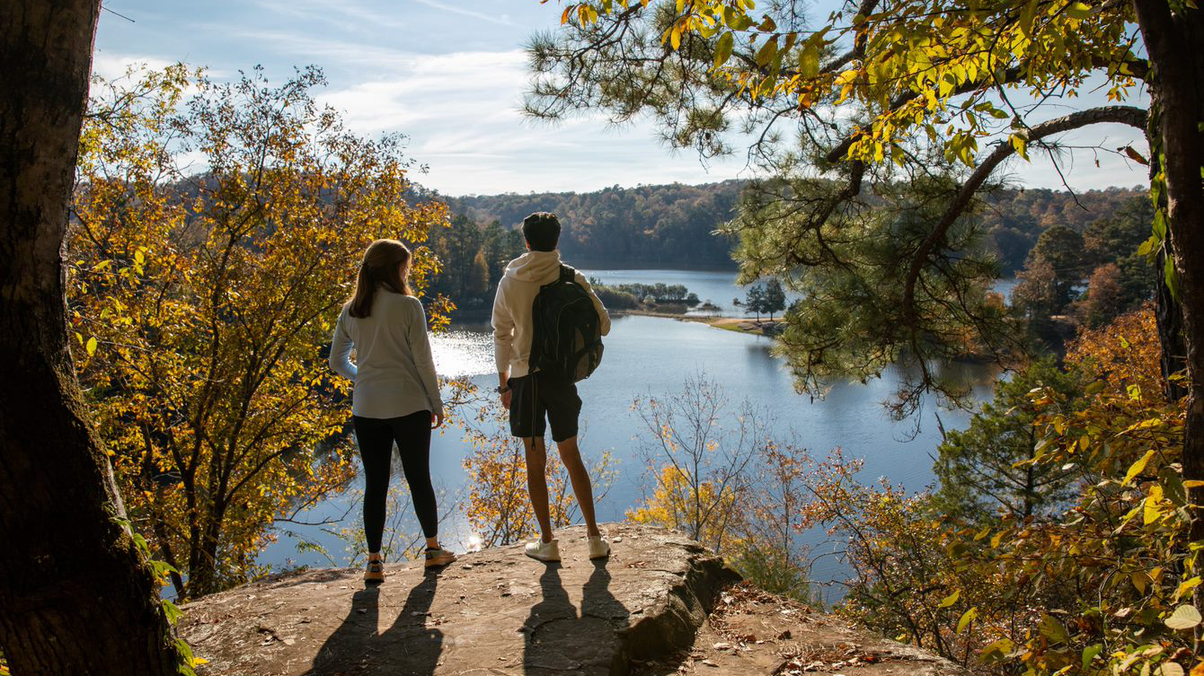 two students standing on a rock overlooking a lake