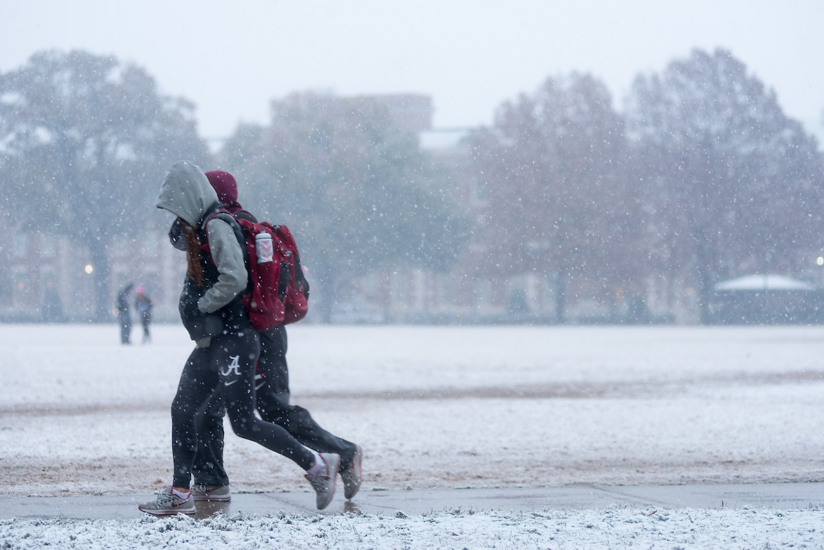 Two students walking to class while snow falls