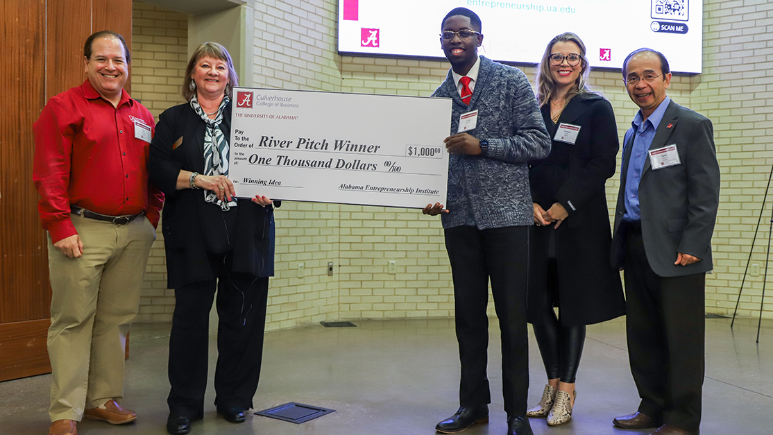 A winner is presented a large check for $1,000 at a River Pitch Competition.