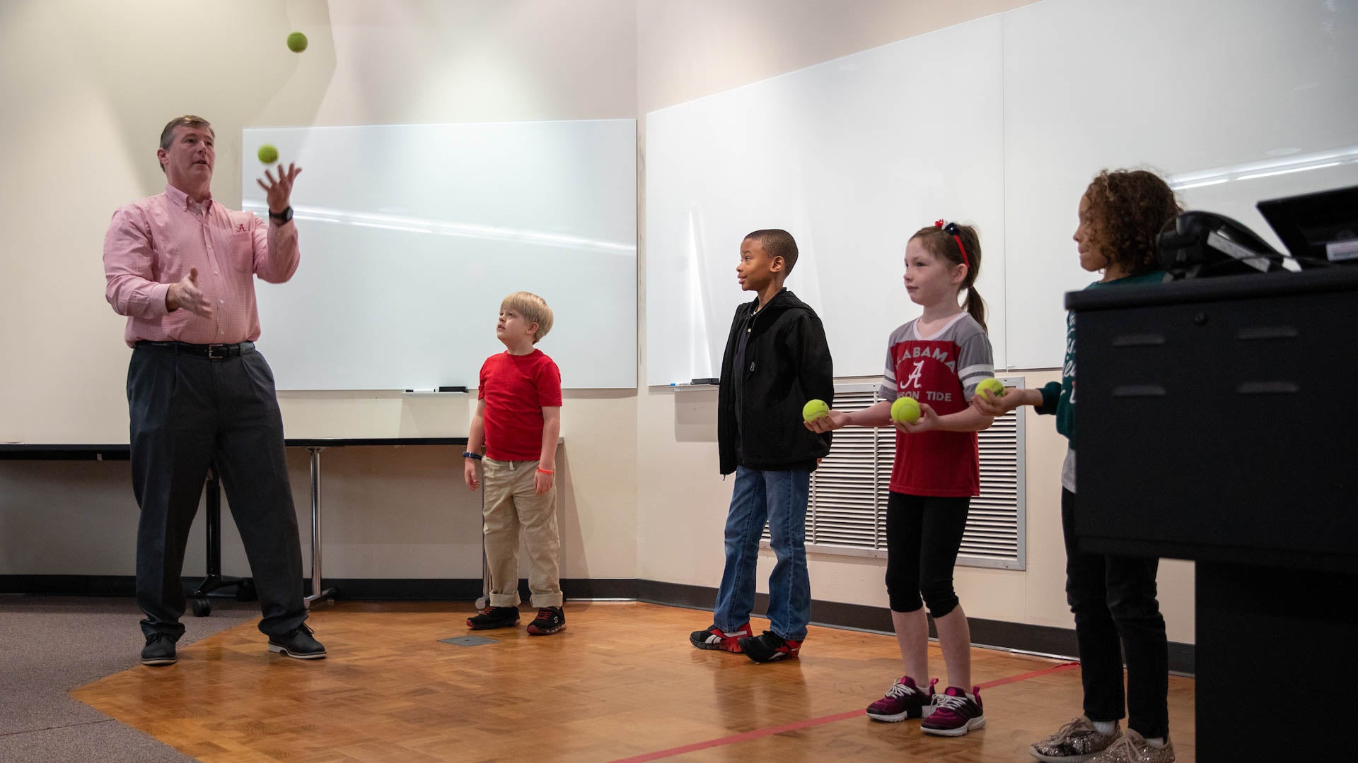 three children watch Dr. Steven Hood juggle tennis balls