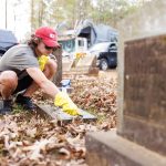 student scrubbing a flat gravestone