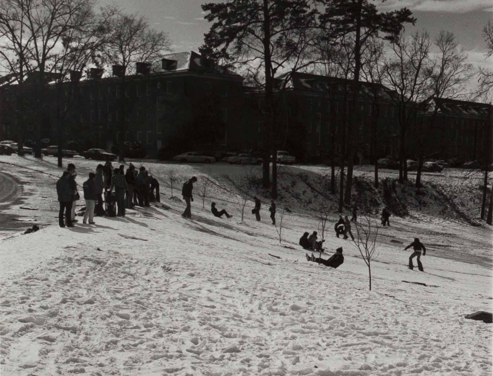 Students sliding down snowy hill