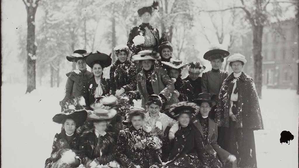women in hats and dresses making snowballs on the Quad