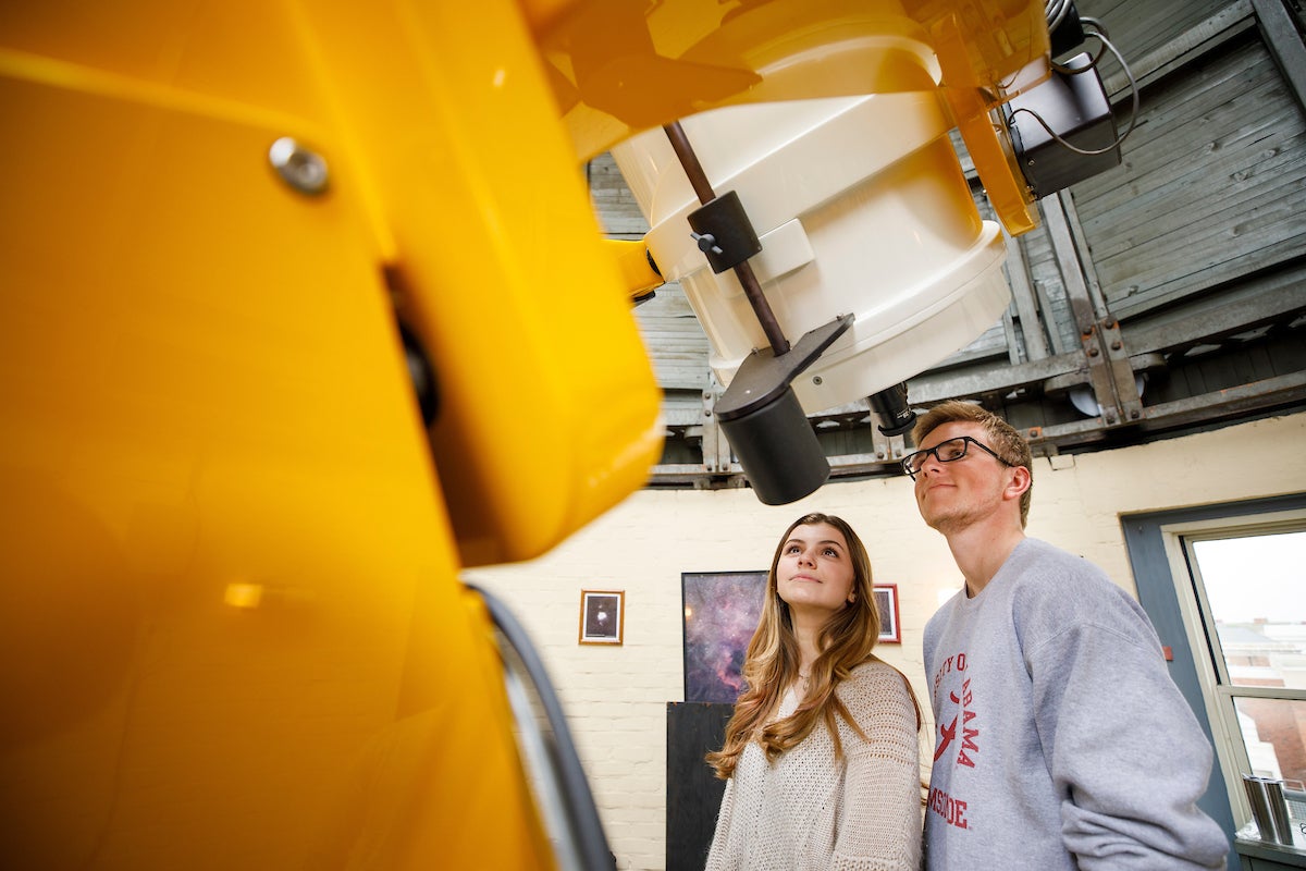 two students look into a telescope