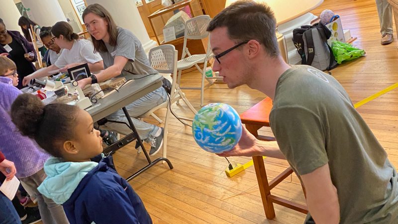 A graduate student shows a child a globe during a previous Family Night at the Museum event
