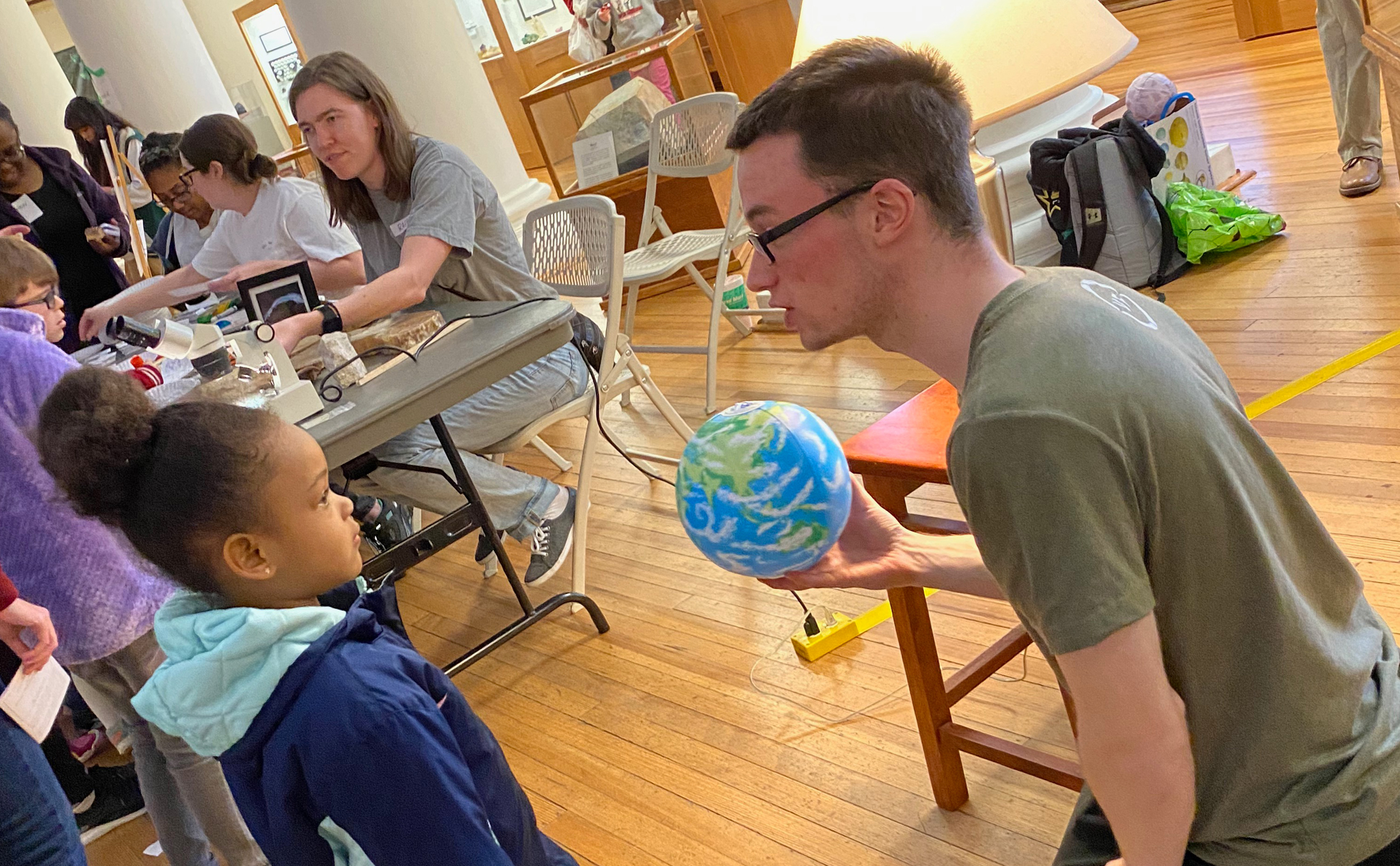 A graduate student shows a child a globe during a previous Family Night at the Museum event