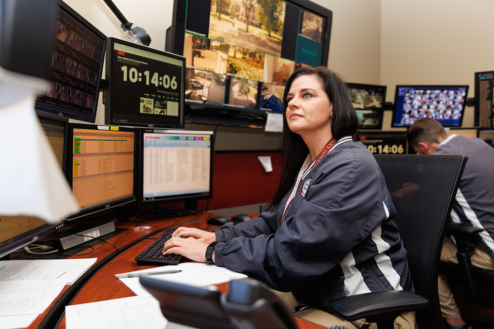 SRA Beverly Porter sits at a desk looking at video monitors.