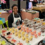 Angel Peterson sitting at a booth selling cupcakes