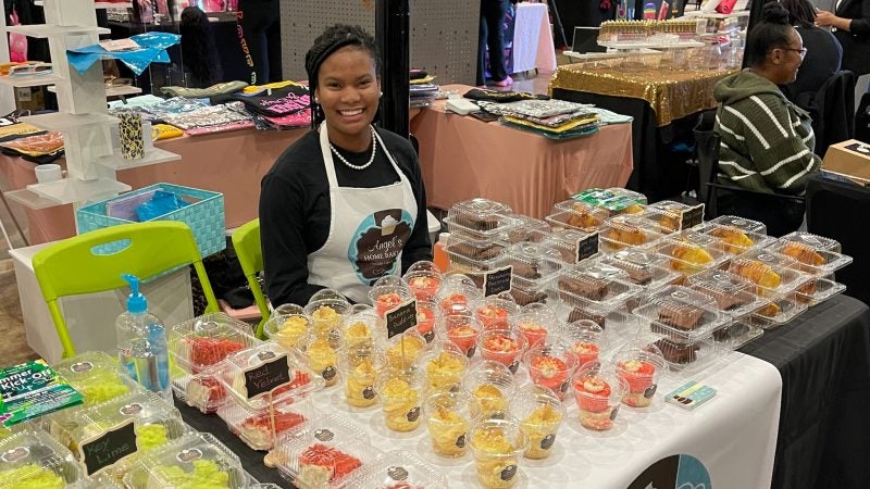 Angel Peterson sitting at a booth selling cupcakes