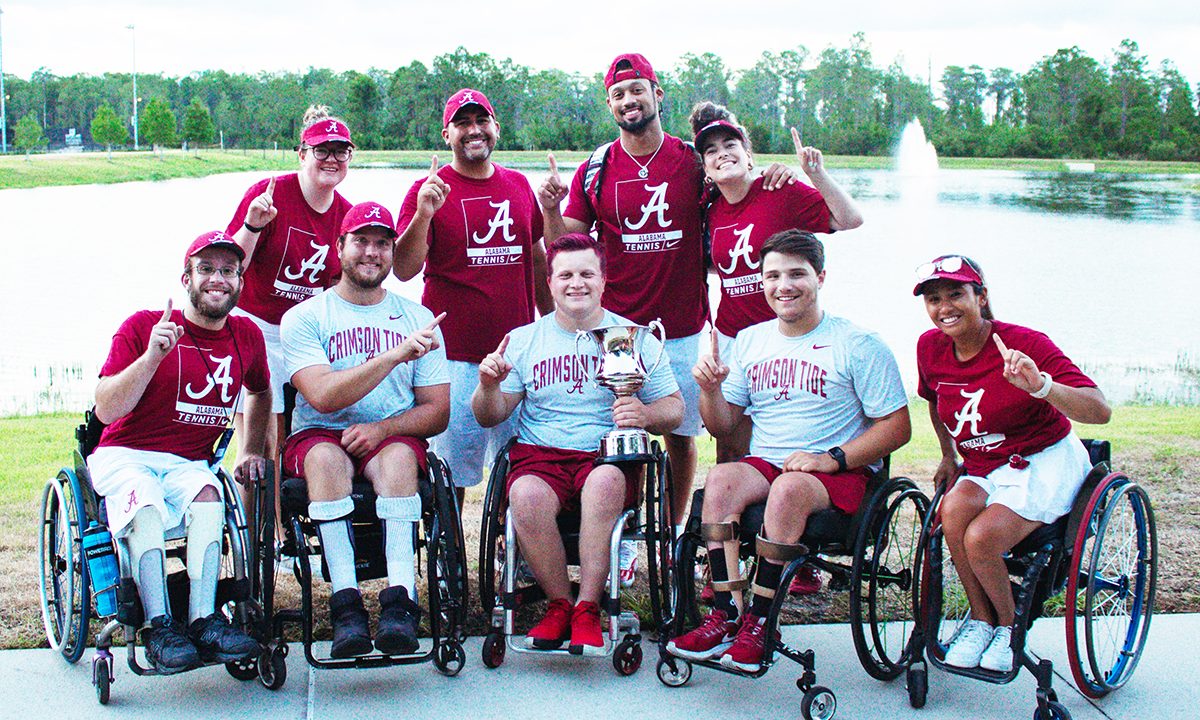 A group of wheelchair tennis players and staff smile for a photo.