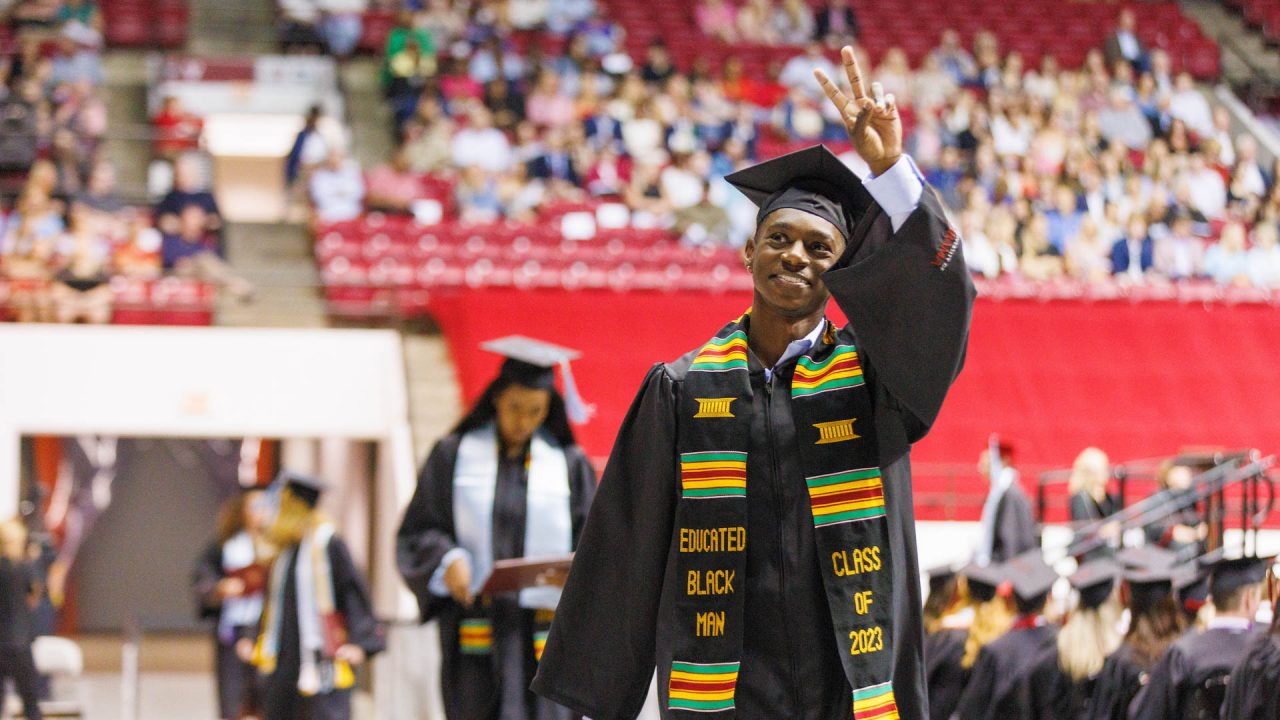 a graduate waves to the crowd at commencement