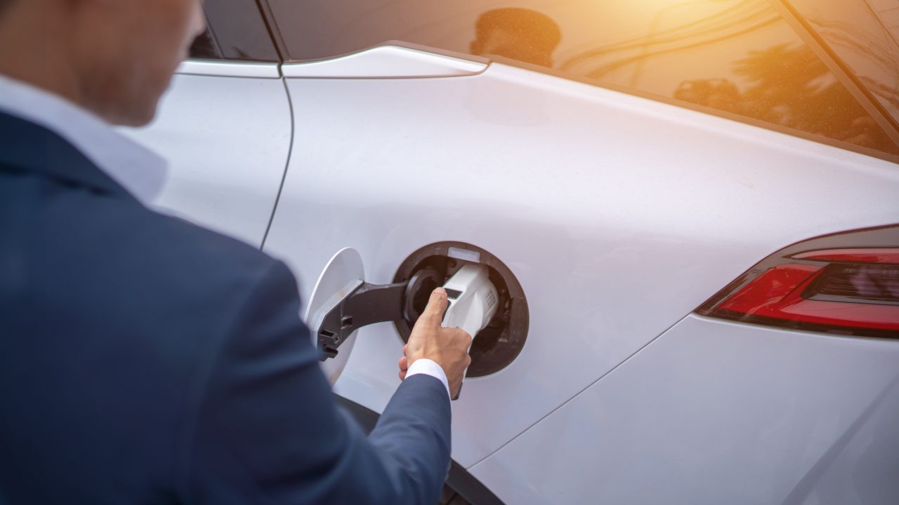 Young businessman charges an electric vehicle at an electric vehicle charging station