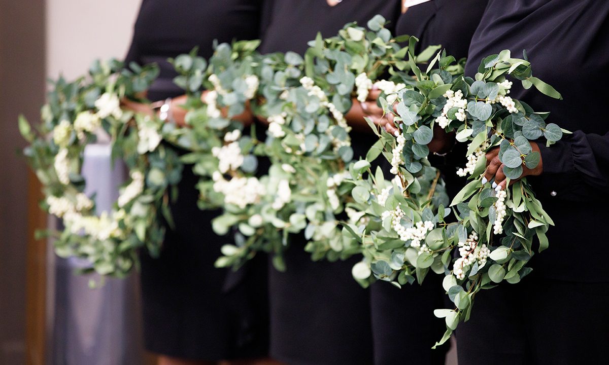 Four people holding identical wreaths