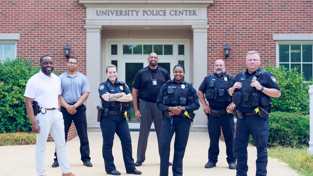 Several University of Alabama Police Department officers posing in front of the police station