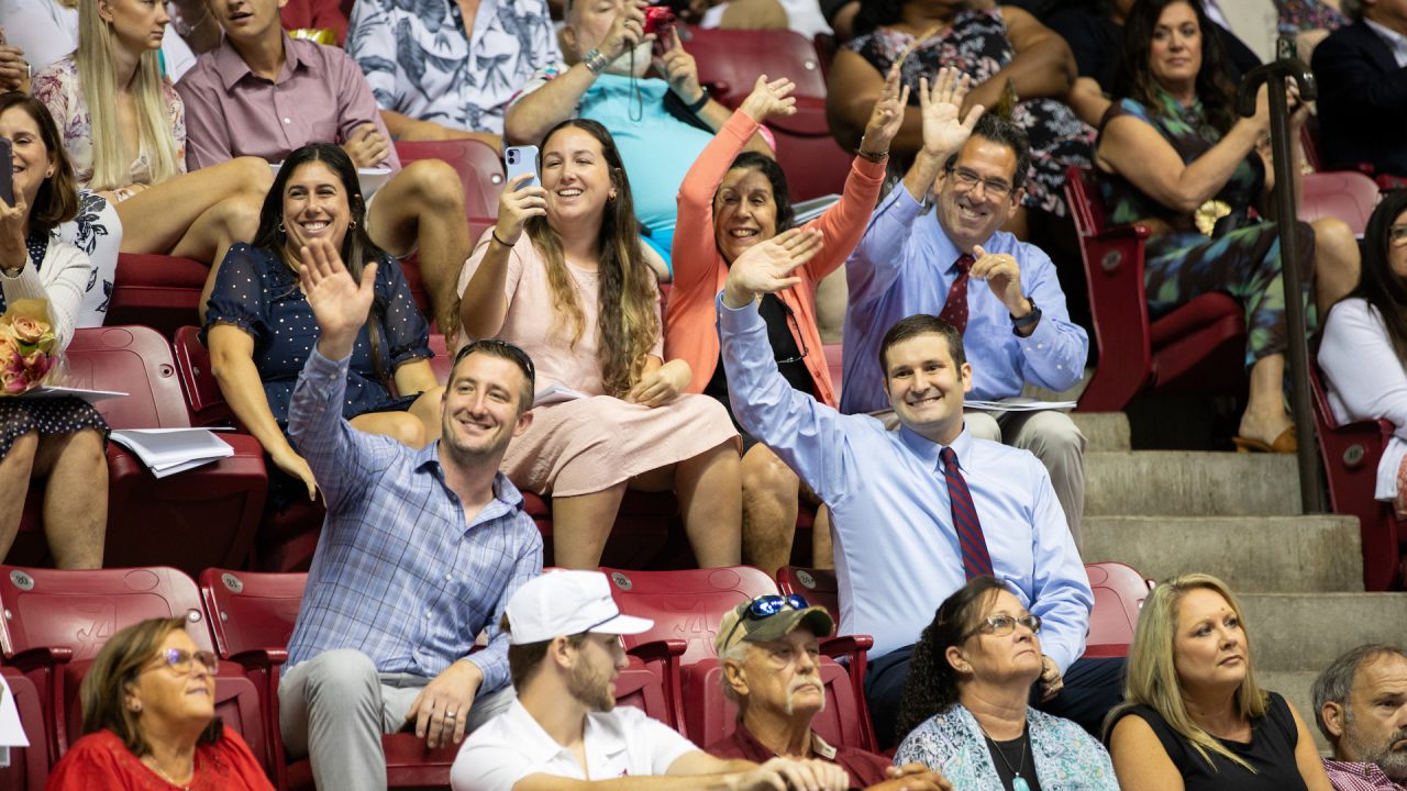 family members in the audience wave to their graduates