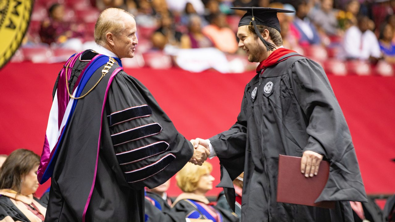 a graduate shakes hands with Dr. Bell