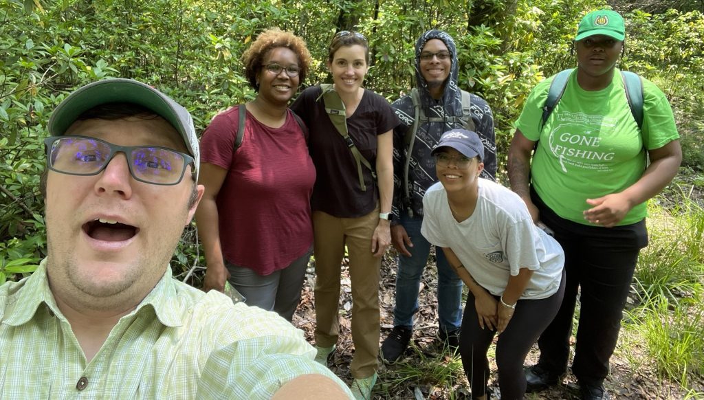 Researchers in a wooded area pose for a selfie.