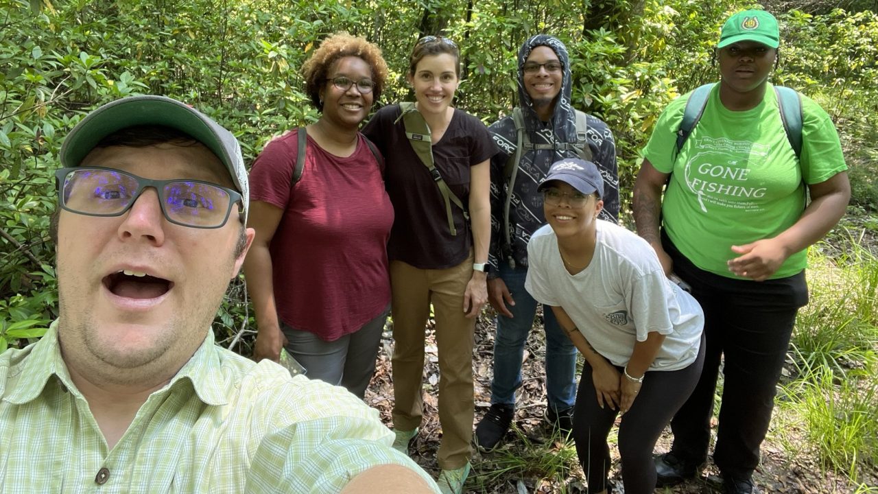 Researchers in a wooded area pose for a selfie.