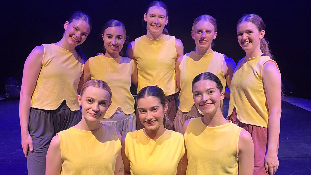 the eight members of Yonder Dance Company wearing yellow shirts on stage