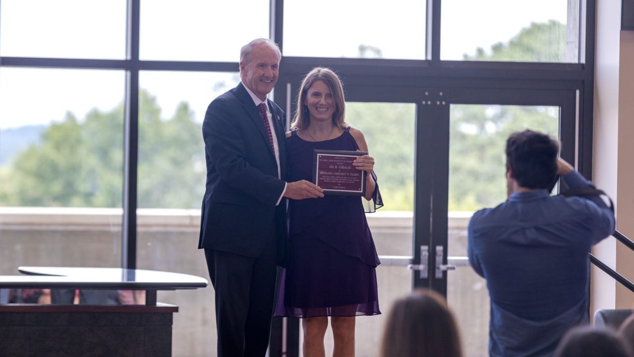 Dr. Bell poses with a faculty award winner holding her award on stage