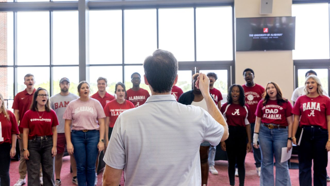 a choral director leads a group of UA students in song