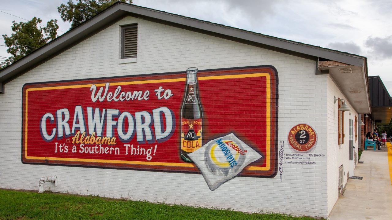 a mural on the side of a building that reads "Welcome to Crawford Alabama. It's a Southern Thing!"