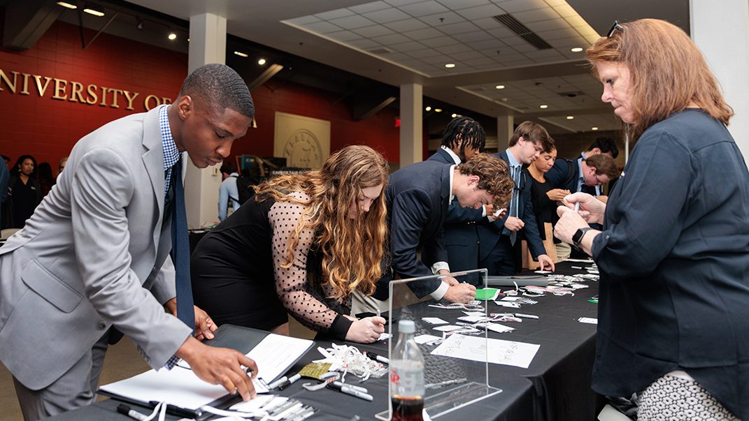 Students fill out name tags at a table during career fair.