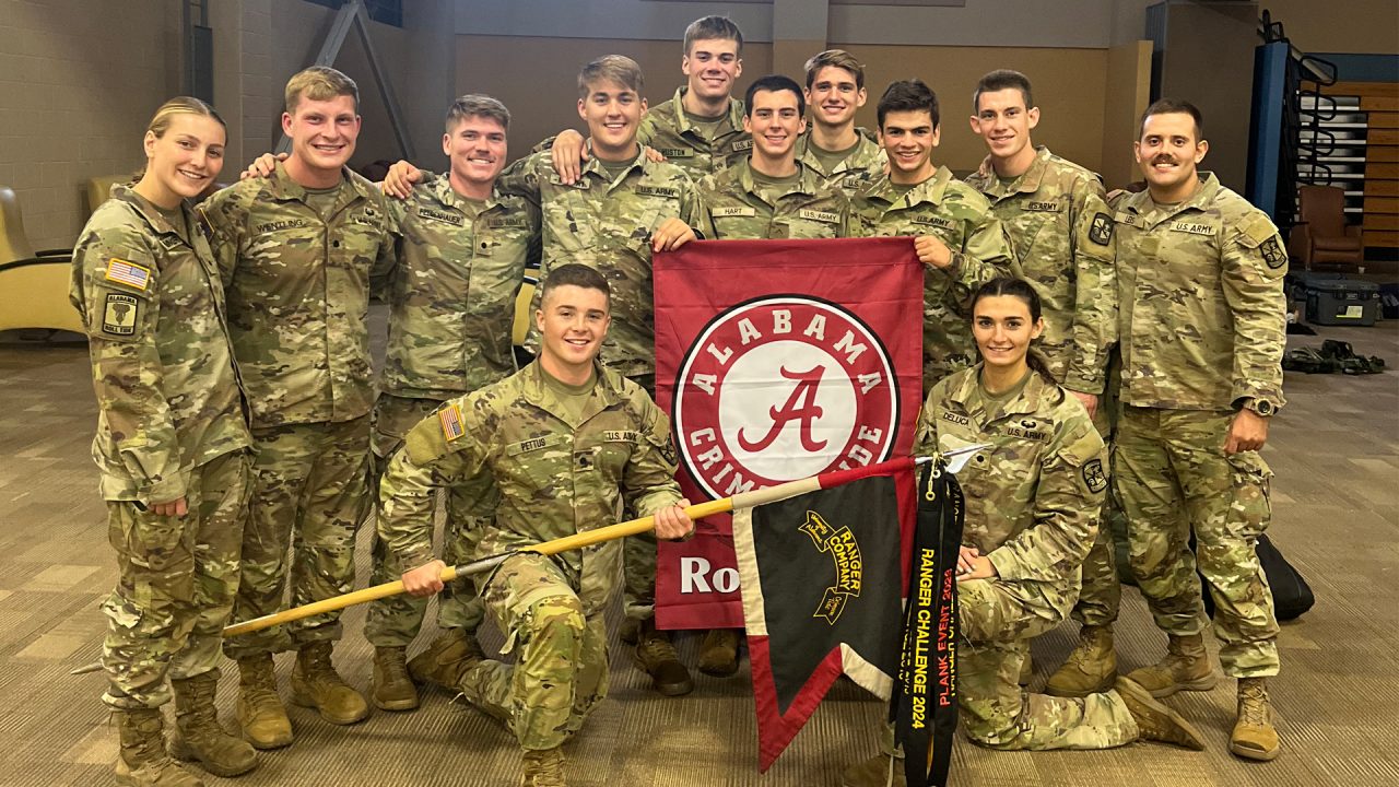 The UA Army ROTC Ranger Team posing with a University of Alabama flag before competition