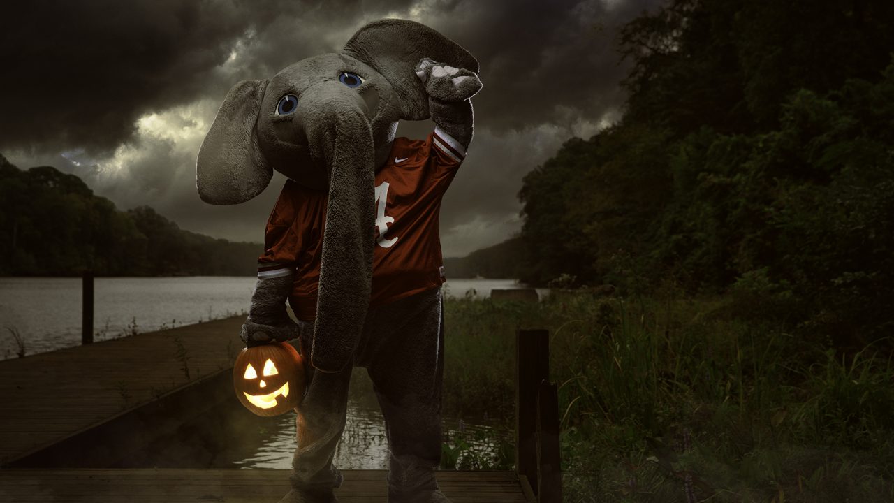 Big Al holds a jack o' lantern standing by an eerie body of water