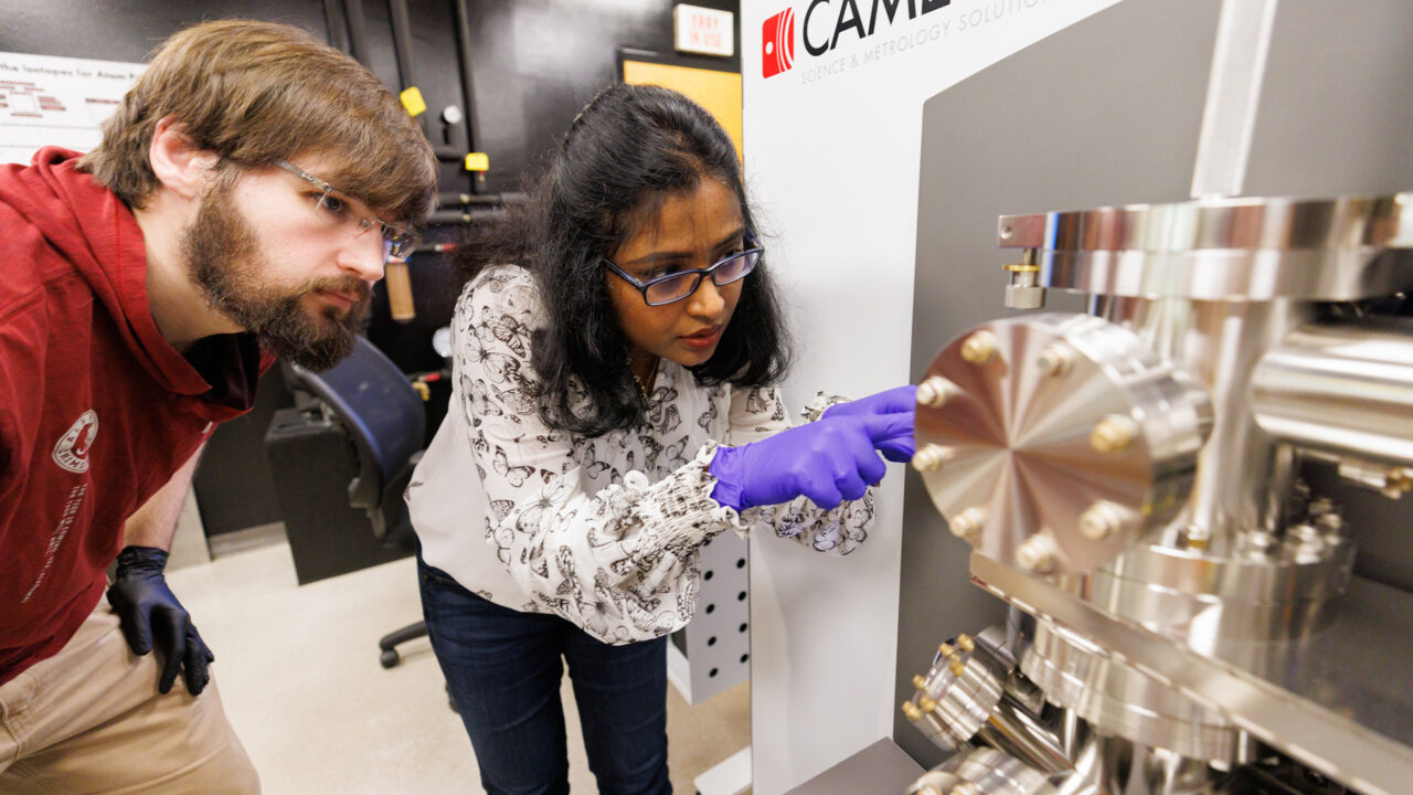 two student researchers examine equipment in the analytical research center