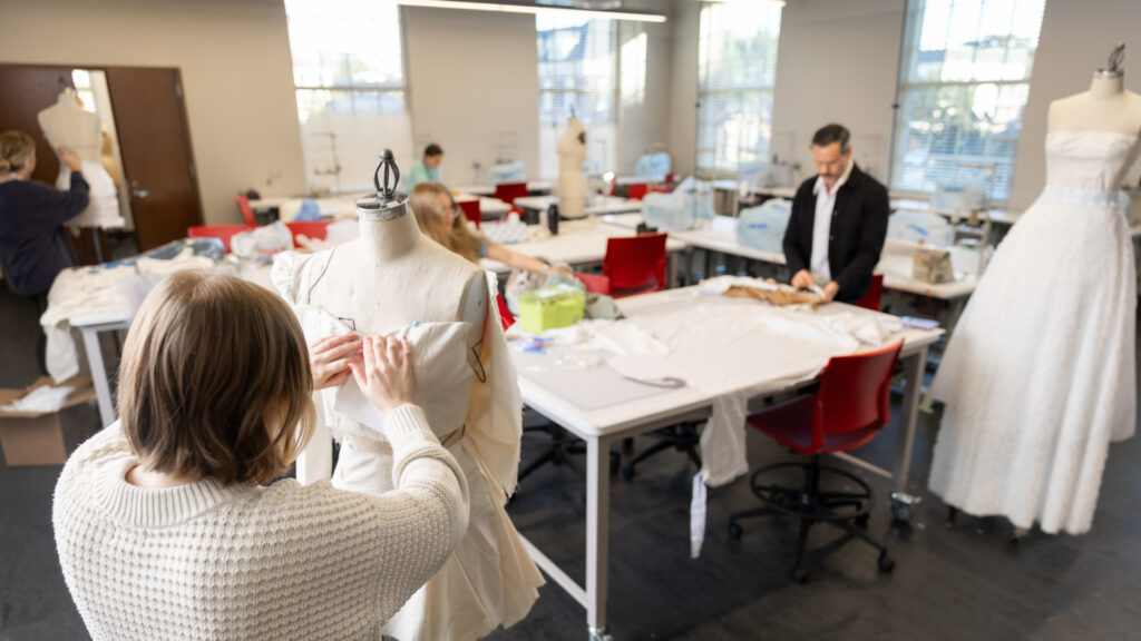 students and faculty work on projects inside a classroom that looks like a fashion deign studio