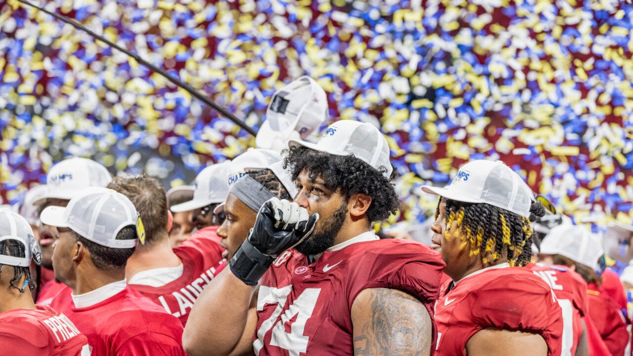 an Alabama football player chokes up as confetti falls around him