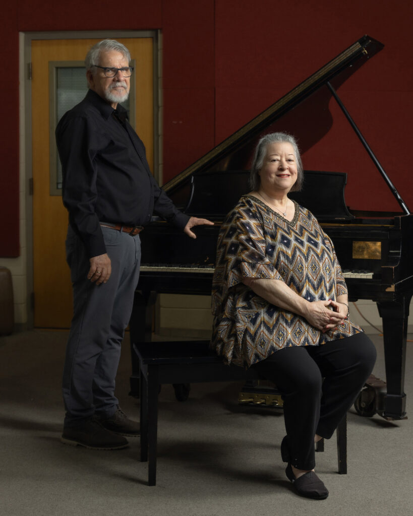 Camilla Huxford sits on a piano bench with Ransom standing next to her