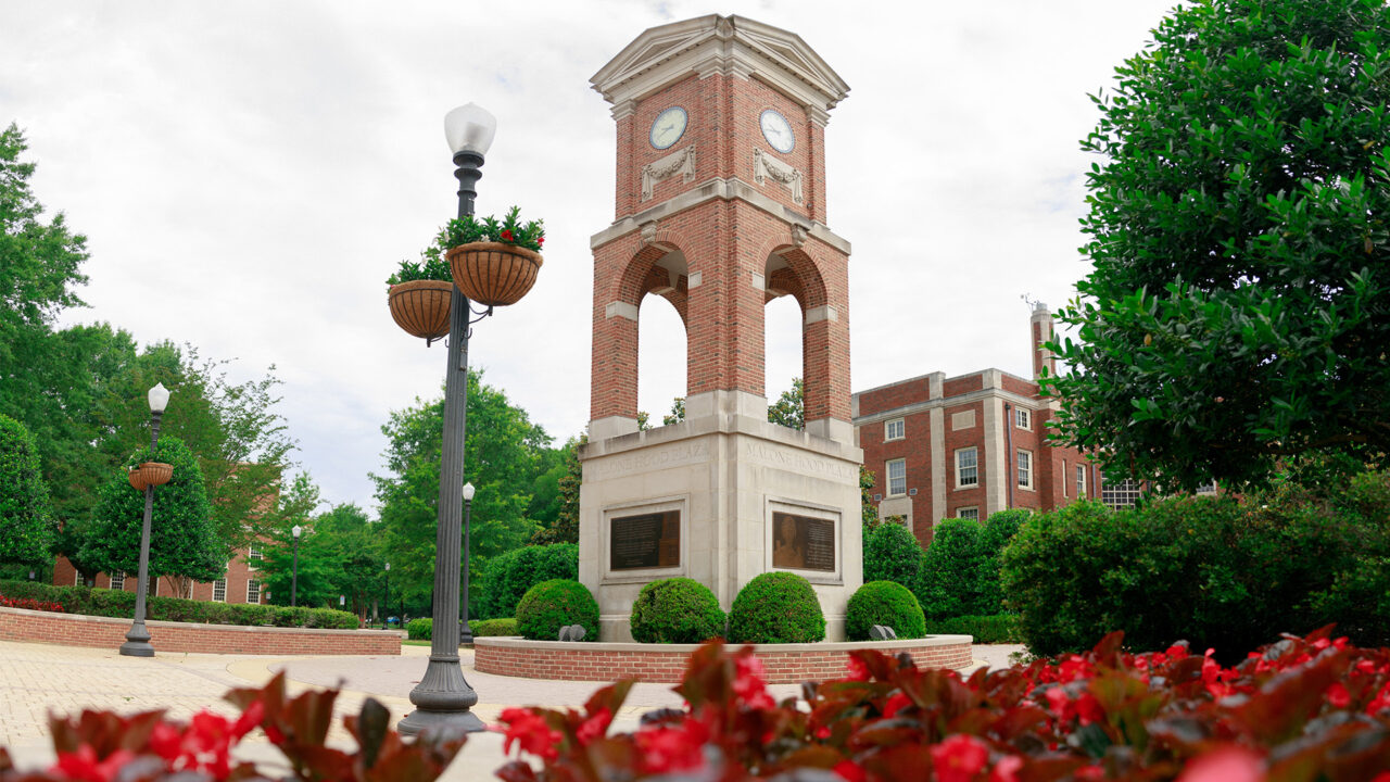 Lucy Clock Tower surrounded by luscious bushes and flowers.