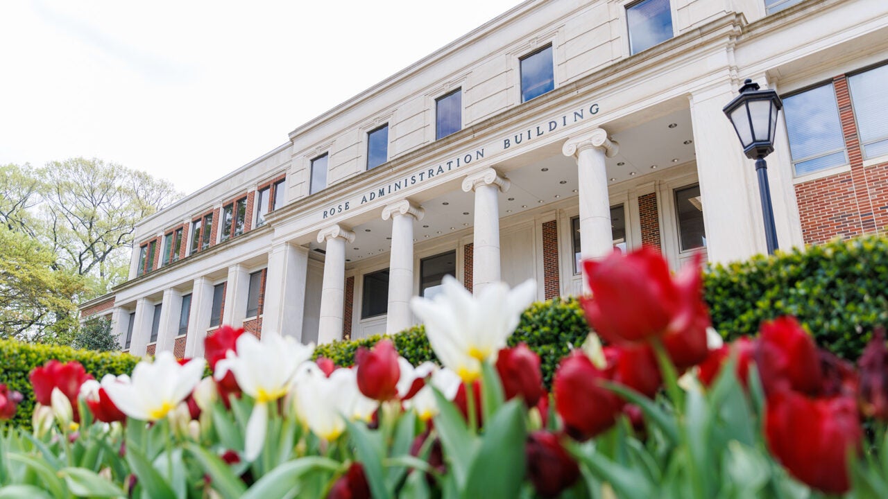 Rose Administration Building with bright white and crimson flowers in the foreground.