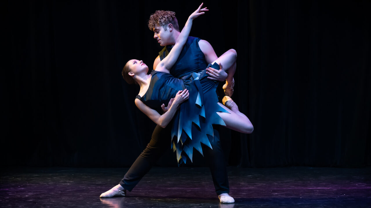 two dancers on stage look into each other's eyes