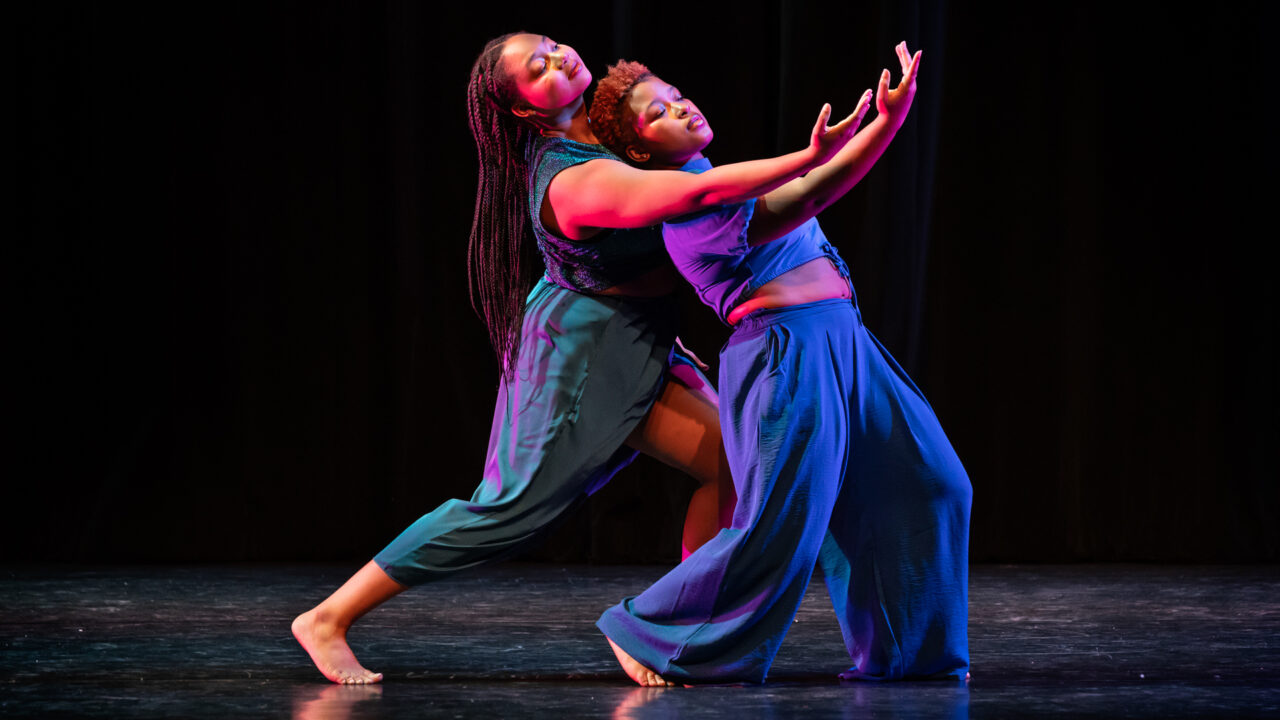 two female dancers embrace on stage