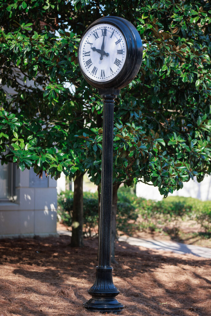 tall black metal clock on campus