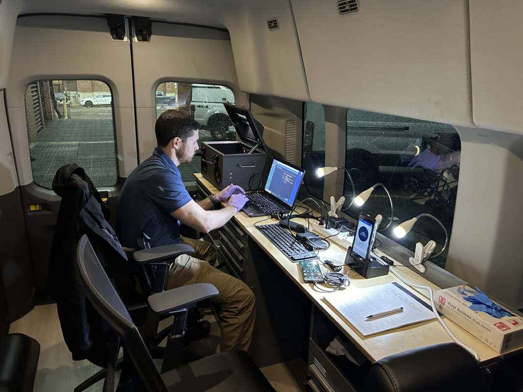 an investigator working on a computer inside a mobile command center