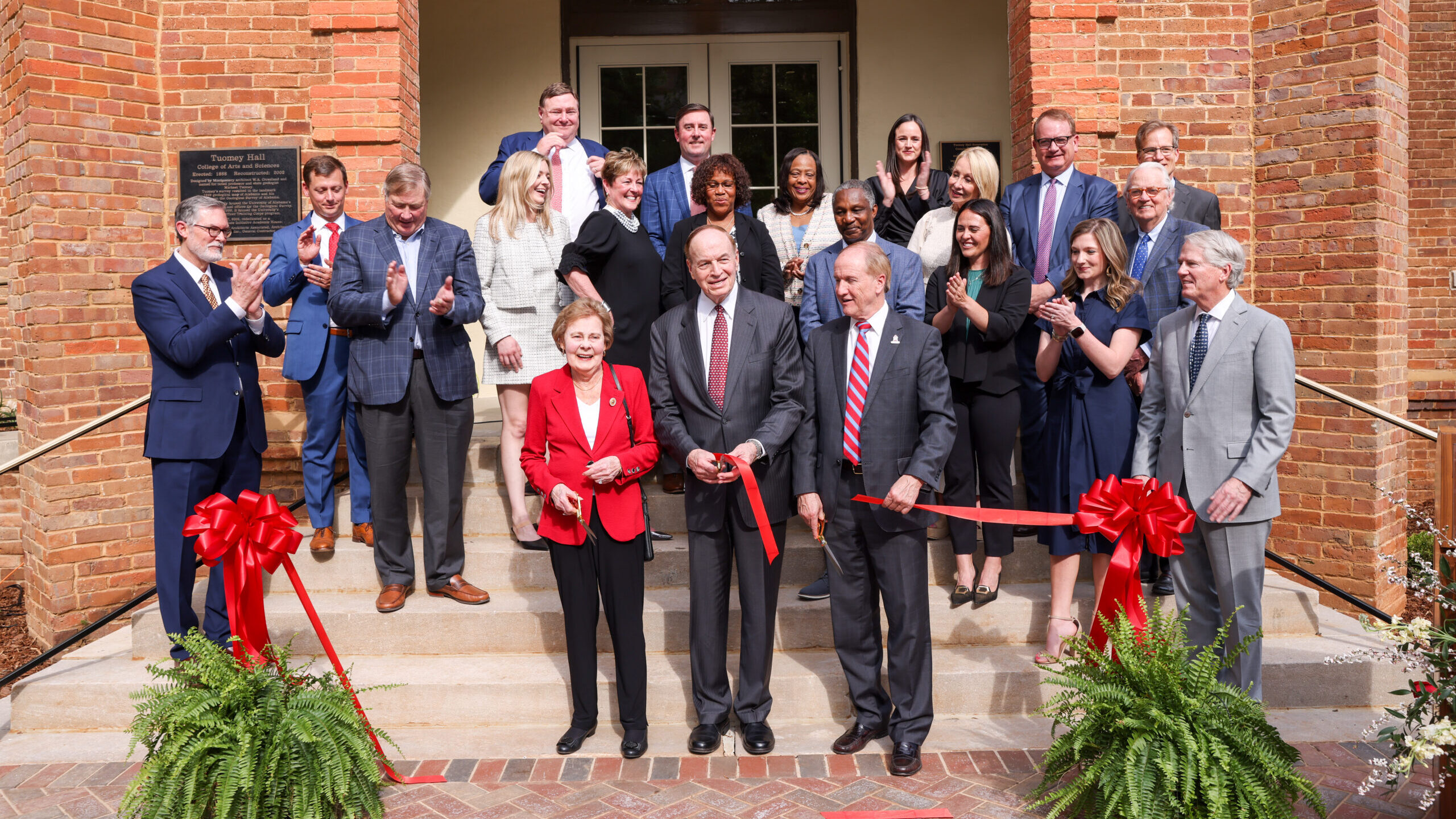 Senator and Dr. Shelby, President Bell and group of people cuts a ribbon outside Tuomey Hall, the new home of the Shelby Institute