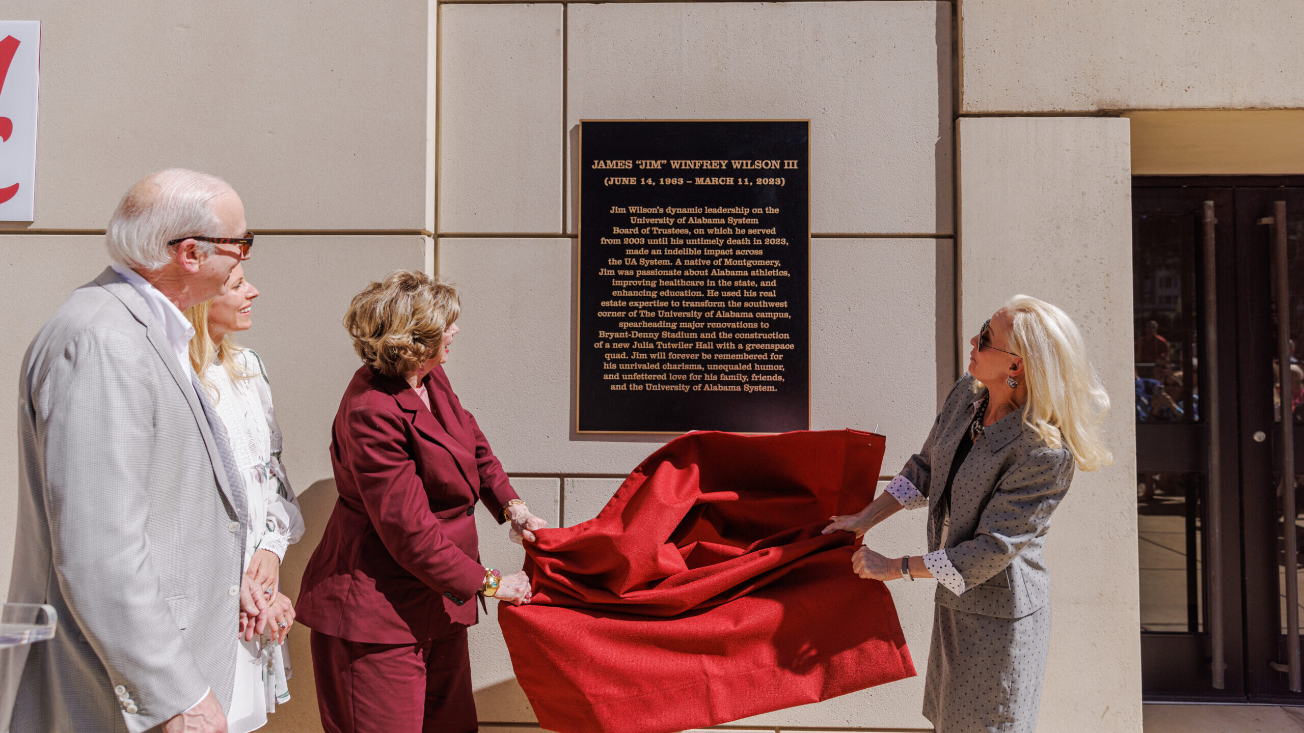 Jim Wilson's family pulling down drape covering the plaque installed on the side of the Bryant-Denny Stadium.