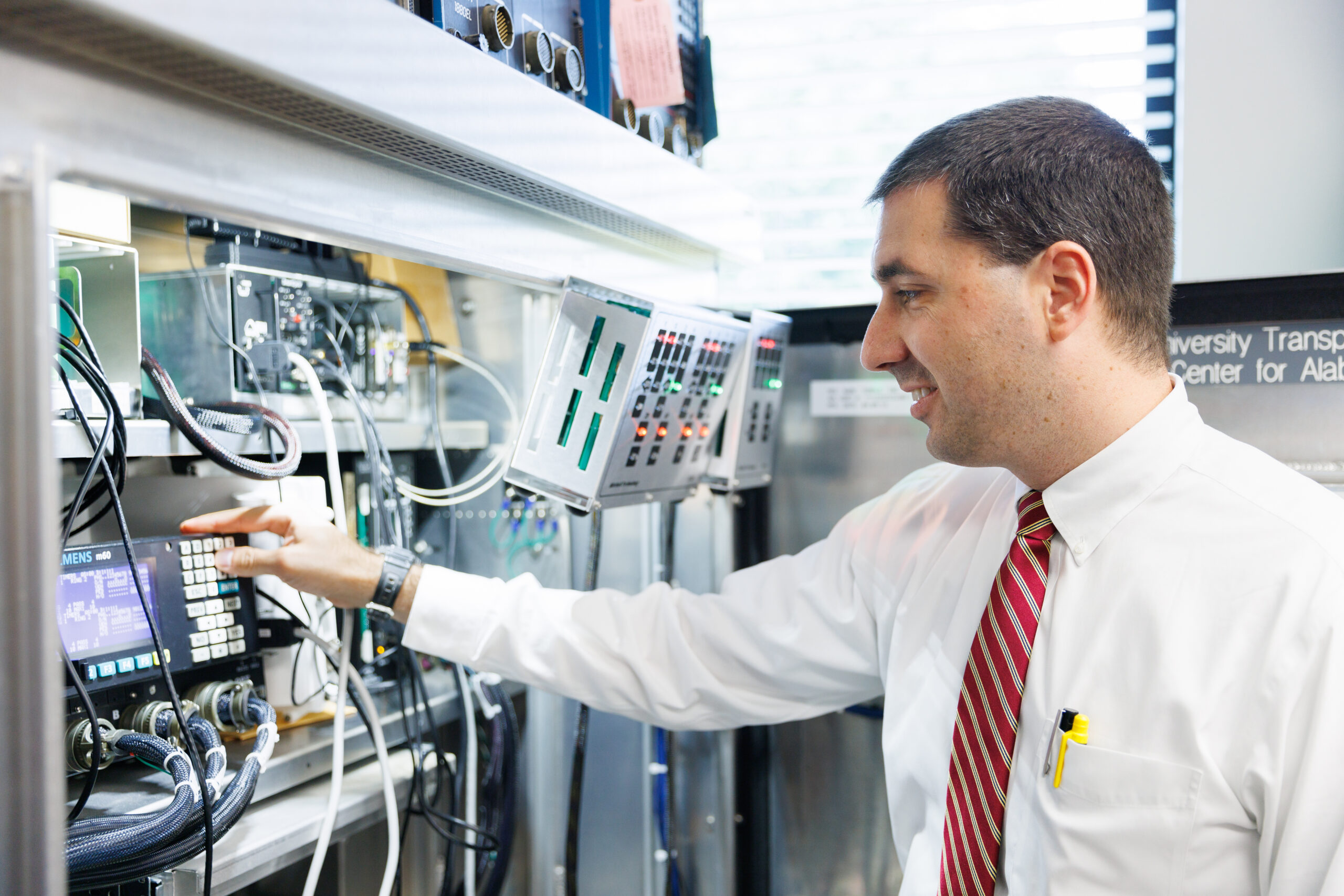 Dr. Alex Hainen working with various control panels and electronic equipment in a laboratory.