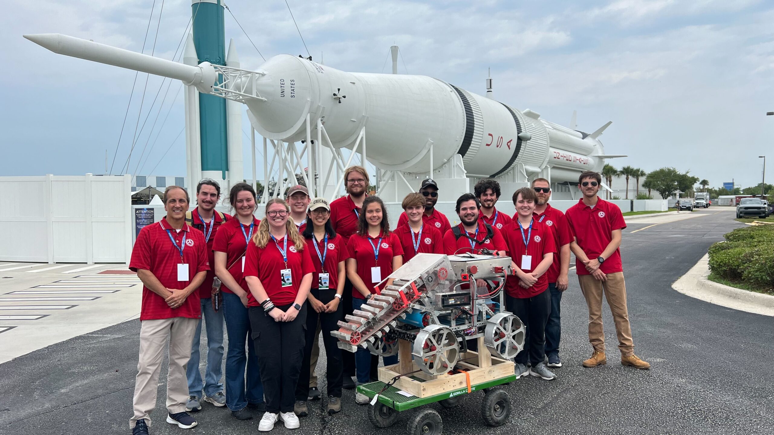 The University of Alabama Astrobotics team stands in front of a rocket with their winning lunar mining rover