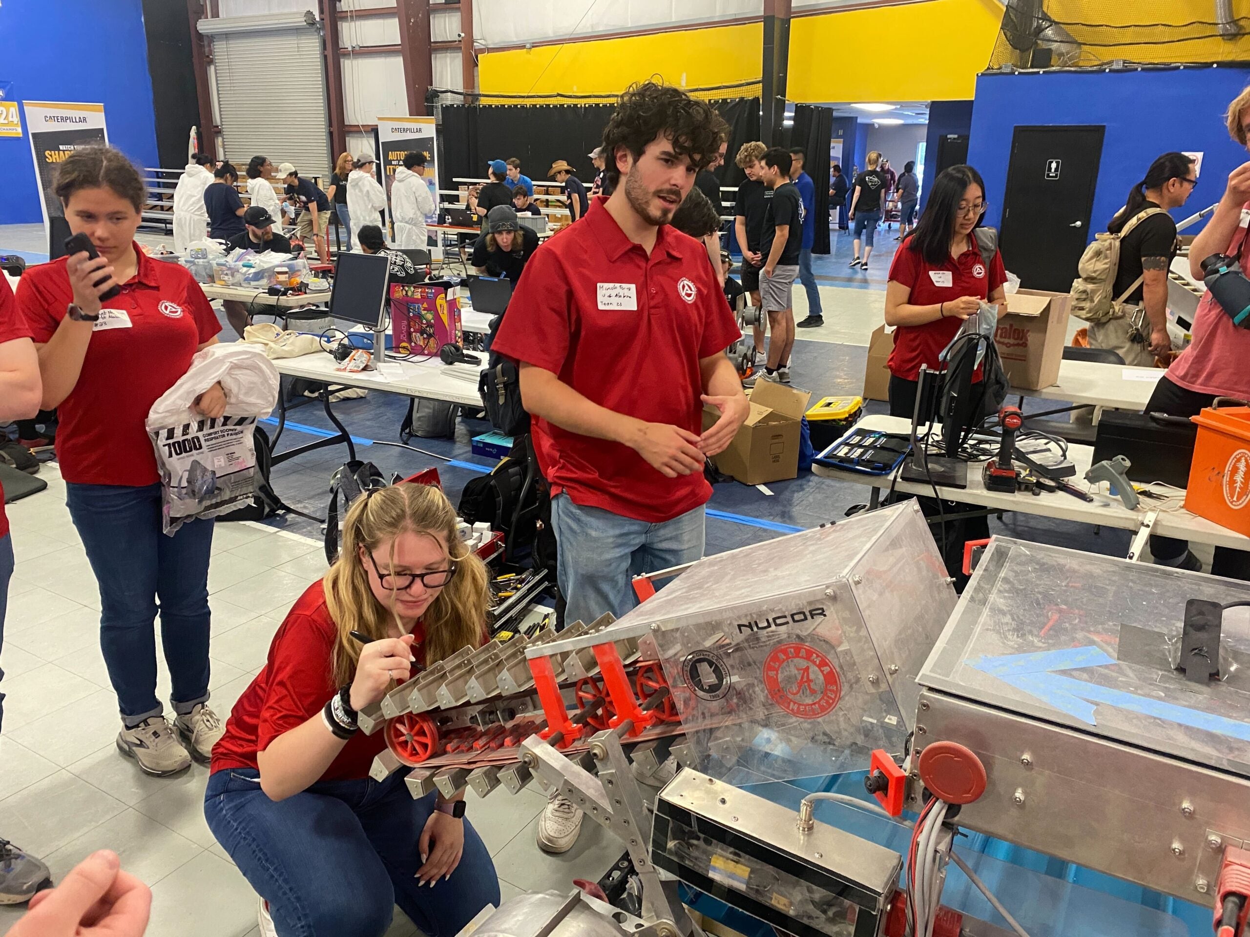 Three Astrobotics team members in red shirts prepare their rover for the demonstration rounds